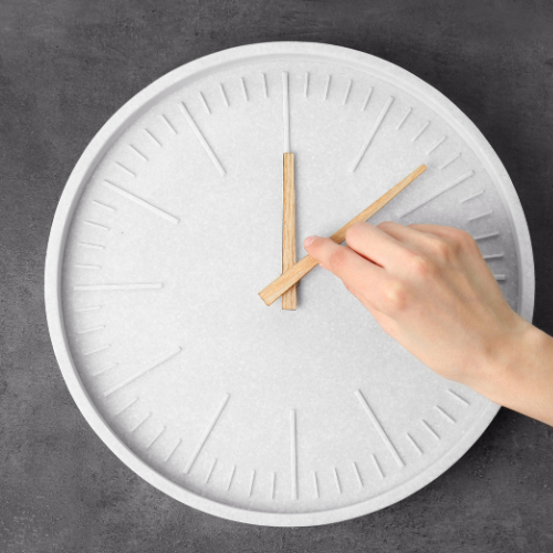 main changeant d'heure sur une horloge pour illustrer l'article sur les conseils pour passer à l'heure d'hiver