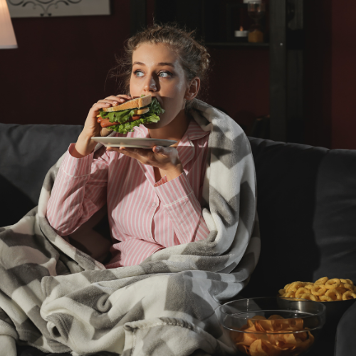 Photo d'une femme mangeant un sandwich et des chips le soir pour illustrer l'article "comment maigrir la nuit"