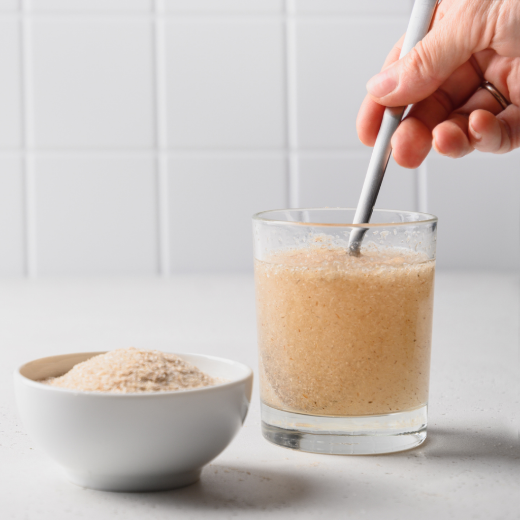 Photo de comment consommer du psyllium avec une cuillère dans un verre d'eau pour illustrer l'article sur les vertus du psyllium